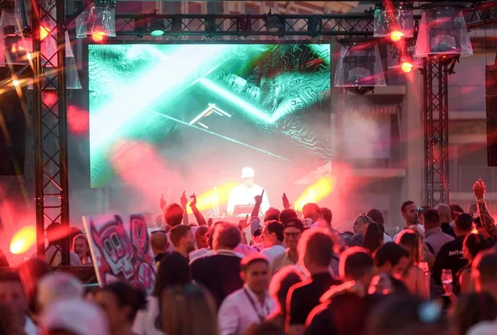 Avondevent tijdens het Monaco Grand Prix-weekend met DJ op podium, lichtshow en publiek voor het scherm